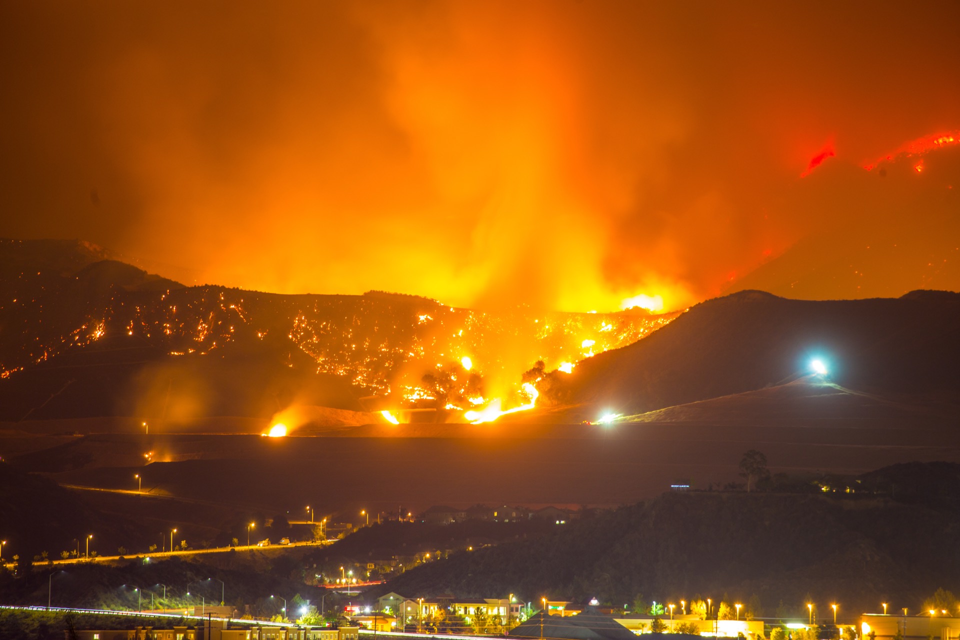 Wildfire burning across a hillside above a Southern California town at night